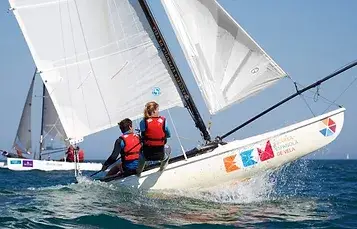 Dos personas navegando en un catamarán de la Escuela Española de Vela de Islantilla.