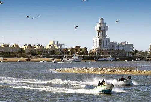 Vista de Isla Cristina con embarcaciones y el edificio del faro al fondo.