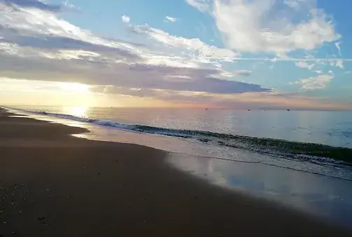 Playa de Islantilla con arena dorada y mar en calma.