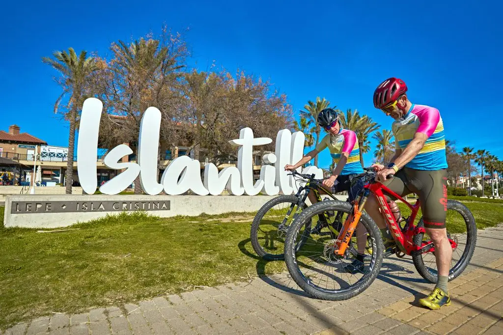 Ciclistas junto al cartel de Islantilla durante una ruta en bicicleta.