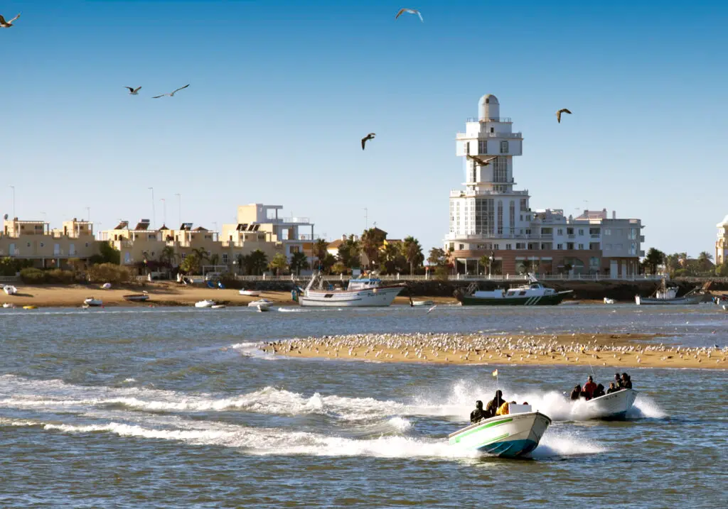 Isla Cristina con embarcaciones y el edificio del faro al fondo.