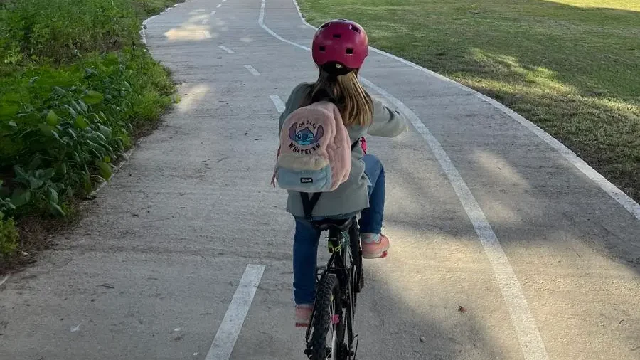 Niña en bicicleta recorriendo un carril bici en Islantilla, Huelva.