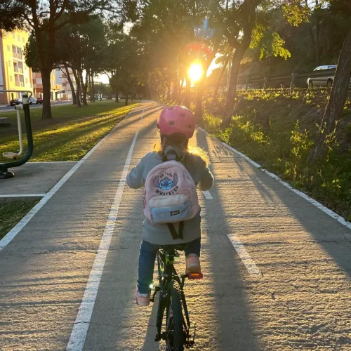 Niña en bicicleta recorriendo un carril bici al atardecer en Islantilla, Huelva.